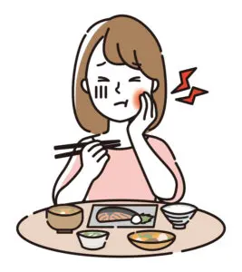 食事中に歯の痛みを感じて頬を押さえる女性のイラスト